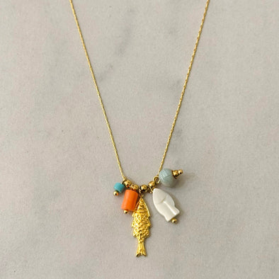 Necklace with gold fish pendant and colorful beads on a light gray background