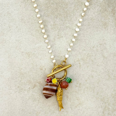 Necklace with various charms on a textured beige background