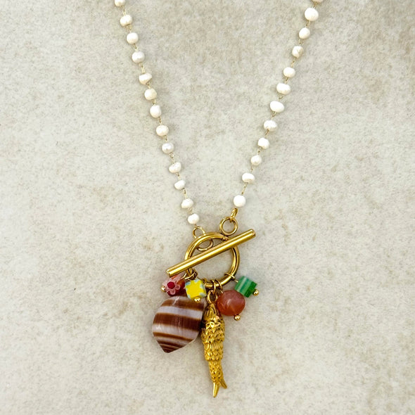 Necklace with various charms on a textured beige background