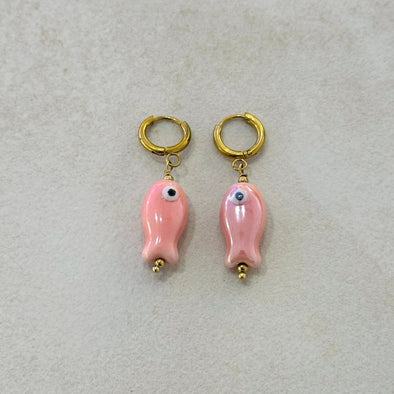 Pair of pink fish-shaped earrings with gold hooks on a light gray background
